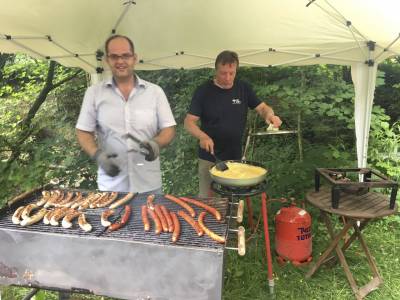 Olaf Khn bereitet das Rhrei zu, whrend auf dem Grill drei verschiedene Sorten von Bratwrsten bruzeln. 